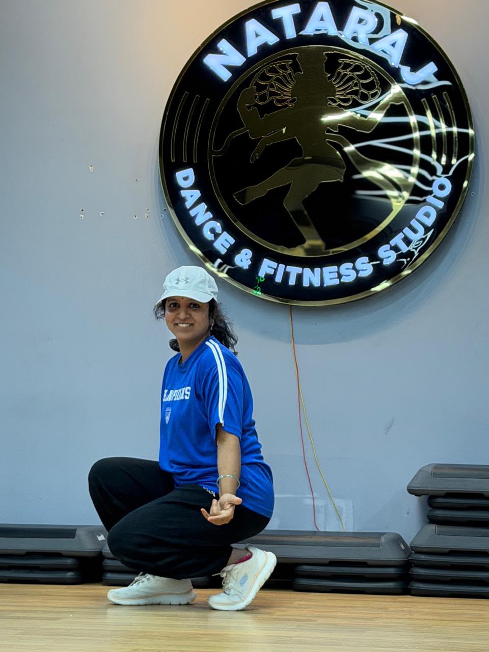 Soumya Zin, founder of Nataraj Dance and Fitness Studio, posing in front of the studio's Nataraj sign